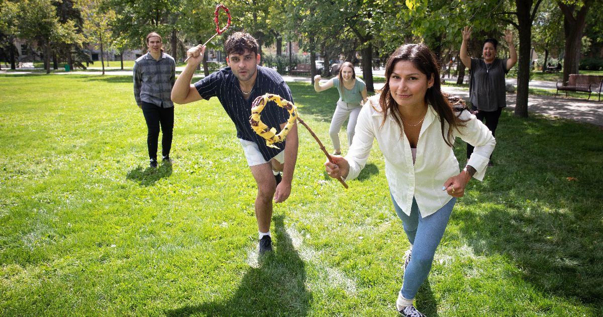 Students playing traditional Indigenous games in an outdoor green space.