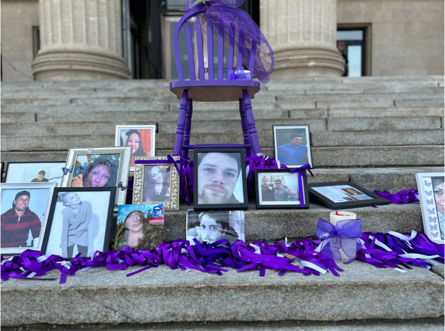 A series of framed photos of people who have died from overdoses were perched on the steps of the Manitoba Legislature to mark Overdose Awareness Day. (Alana Cole/CBC)