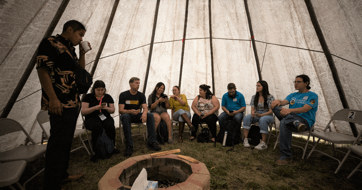 Members of the UM campus community gather inside a tipi