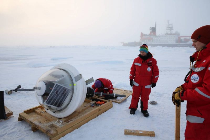 Two Arctic researchers deploying a buoy for their studies.