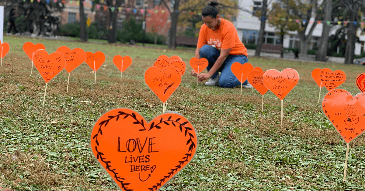 Orange hearts with messages for truth and reconciliation "planted" in a grassy field.