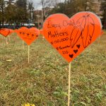 Orange hearts with messages of truth and reconciliation in a grassy field.