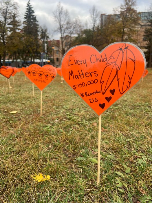Orange hearts with messages of truth and reconciliation in a grassy field.