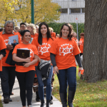 A group of people wearing orange t-shirts march toward the camera.
