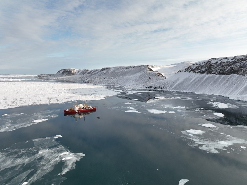 A ship set in ice water amid the surrounding Arctic environment.