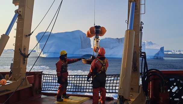 Two researchers deploying a mooring into the Arctic sea.