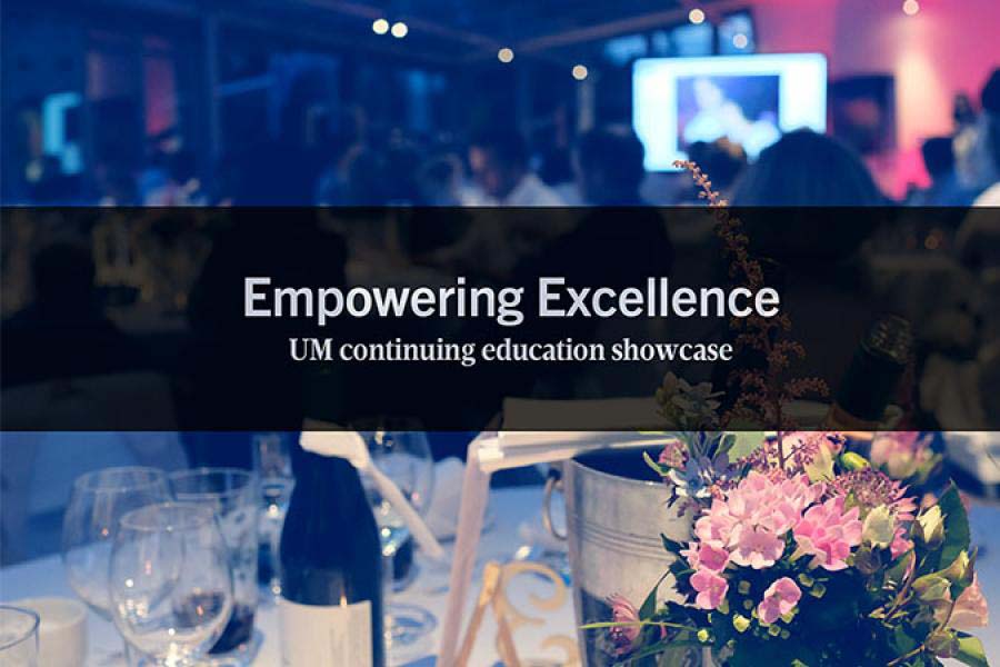 Photo of a table at a formal event, with wine bottle, flowers and Empowering Excellence UM continuing education showcase on it.