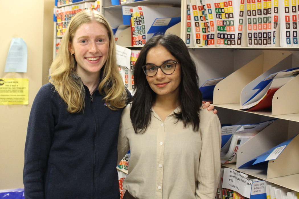 Guneet Uppal and Diana Prince pose for a photo. File folders are on shelves behind them.