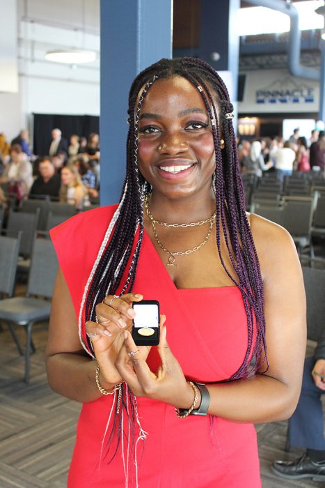 Vivian Umeohabike holding her University of Manitoba nursing pin.