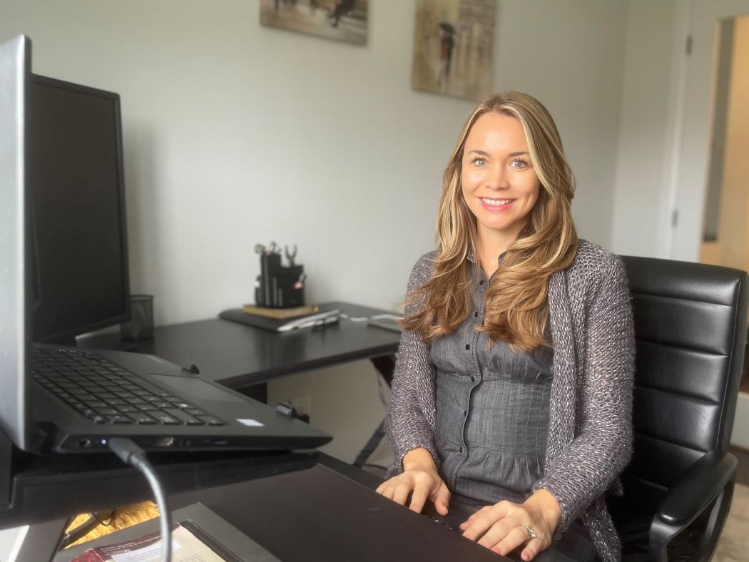 Dr. Ana Ludke sits at a desk with her hands on the computer keyboard.