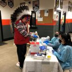 Chief David Monias of Pimicikamak Cree Nation, wearing a headdress, checks in to be vaccinated against COVID-19 in 2021.