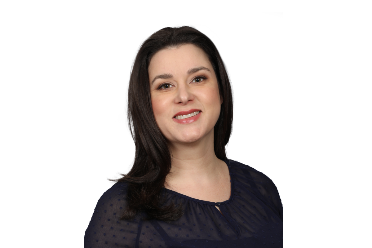 Woman with dark hair and blue shirt standing