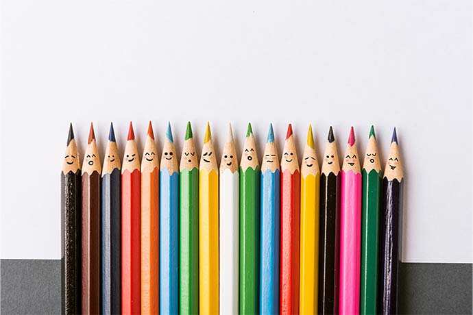 A row of many coloured pencils with faces on them.
