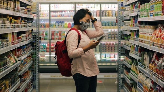 Student in a grocery store looking concerned about food prices.