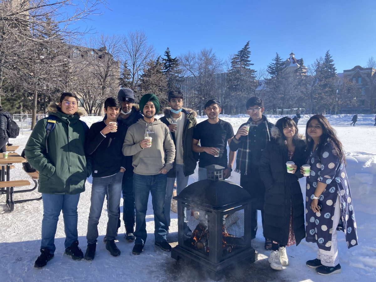 A group standing on the quad smiling with hot chocolate