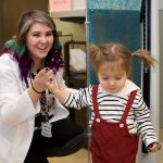 Physician with a young child wearing pigtails.