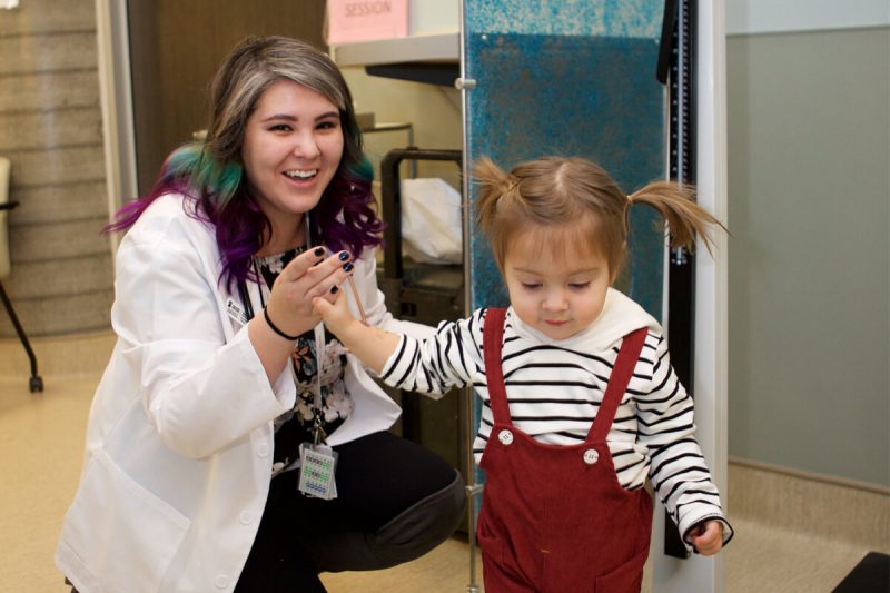 Physician with a young child wearing pigtails.