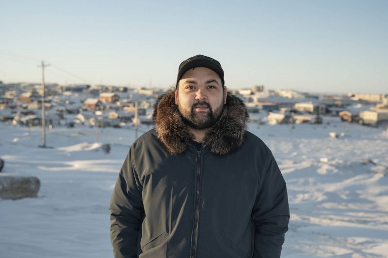 Inuk man stands outside in Northern community