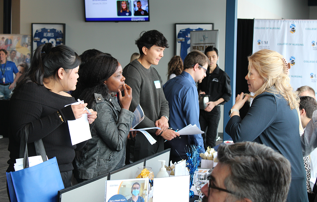 Students discuss career options with a professional at a career fair booth.