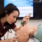 A respiratory therapy student performing an endotracheal intubation on a mannequin.