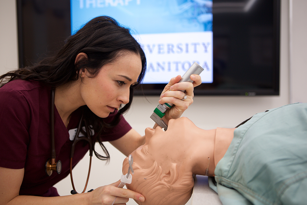 A respiratory therapy student performing an endotracheal intubation on a mannequin.