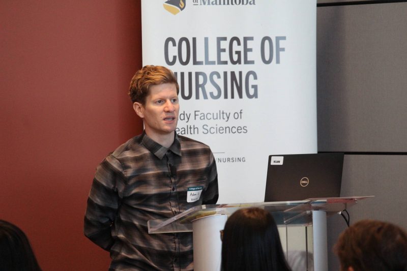 Adam Brandt speaks in front of a College of Nursing banner.