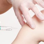 A vaccination being delivered into an arm via a needle.