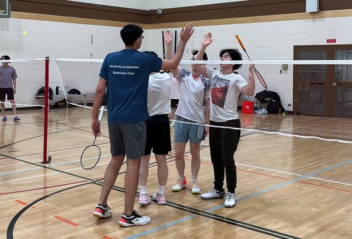 a group of badminton players high-fiving after a game