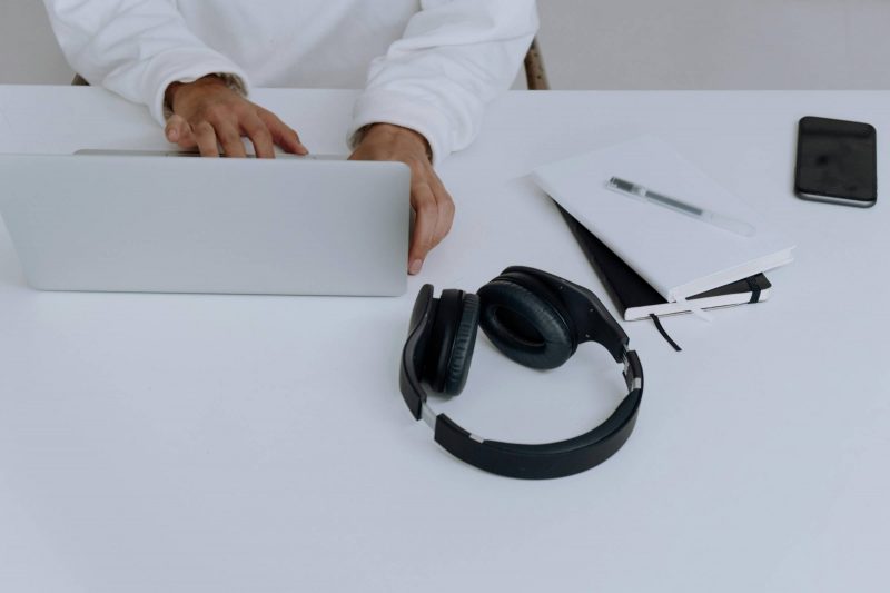 Close-up of computer, hands and headphones.