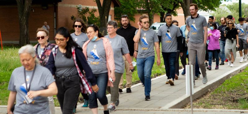 Group of people in matching Sneaker Day shirts walking through campus.