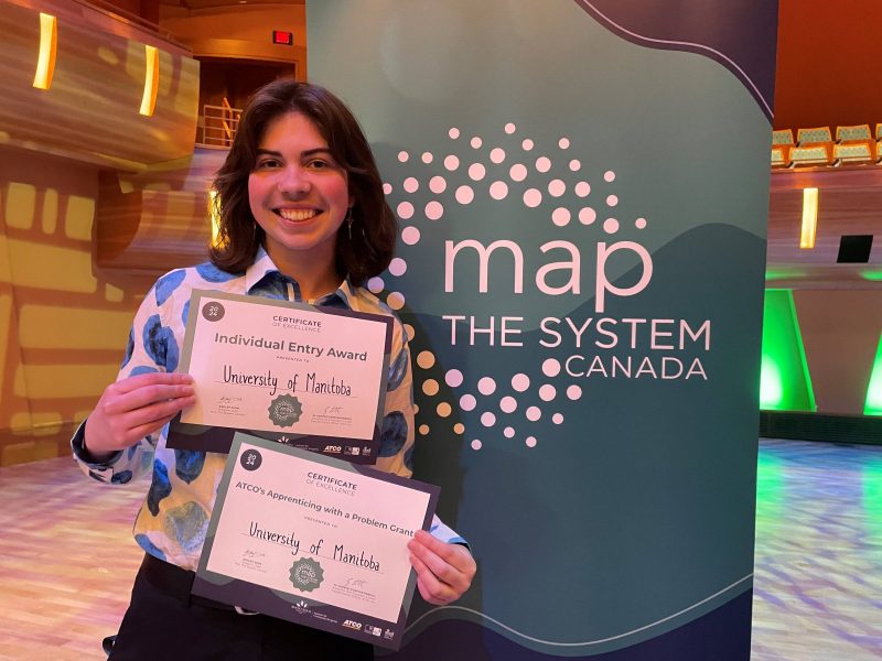 Theodore Biggs-Engel posing with two awards at Map the System