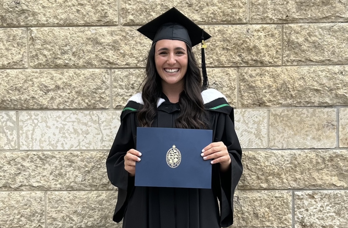 Photo of Juris Doctor Class of 2024 Valedictorian, Kali Faingold wearing a cap and gown and holding her degree in an official UM folder.