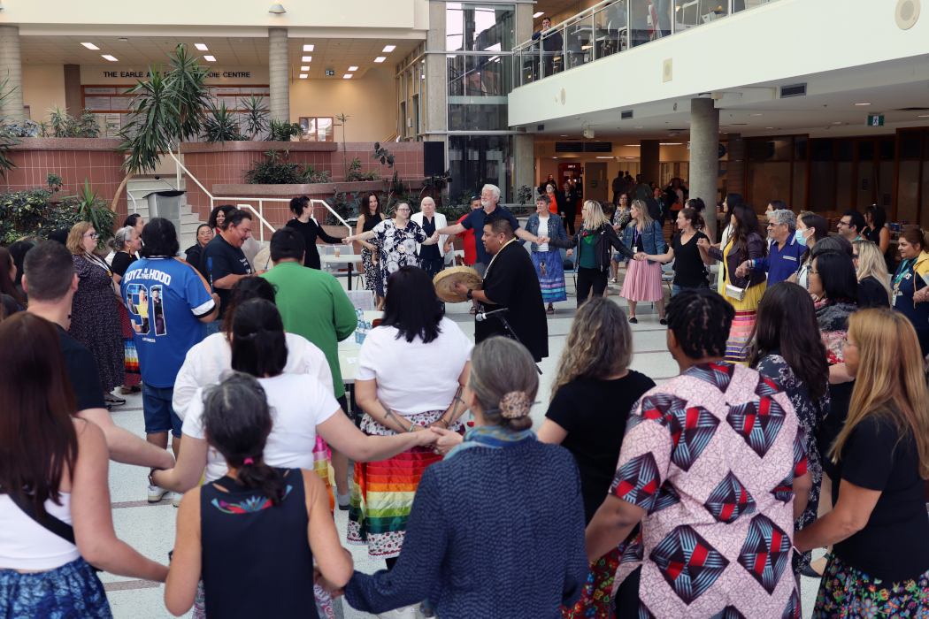 Dozens of people join hands and form circles around drummers in the middle.