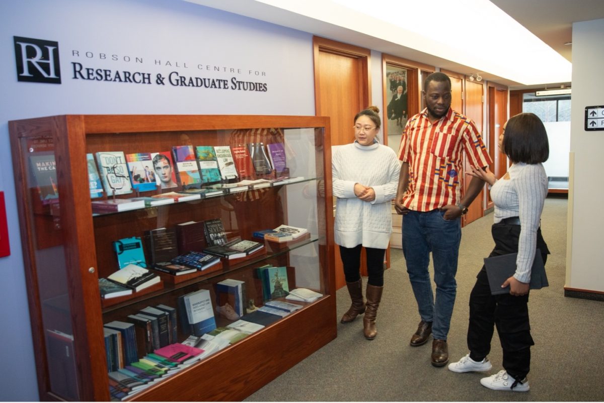 three graduate students talk in the hallway of the Robson Hall Centre for Research and Graduate studies