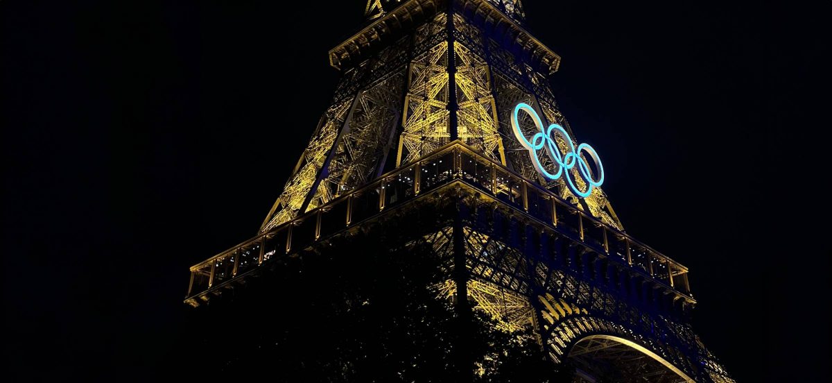 A shot of the Eiffel tower lit up at night with the olympic rings