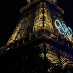 A shot of the Eiffel tower lit up at night with the olympic rings