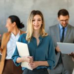 Photo of a professional woman holding her notes and standing in front of four business colleagues