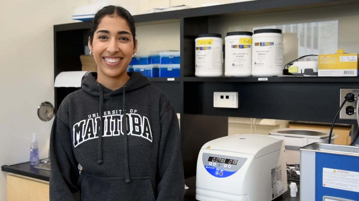 Shubhneet Thind, smiling at the camera, standing in a biochemistry lab.