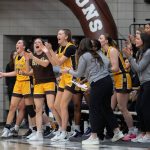 The Bisons women's volleyball team celebrates on the sidelines after a basket