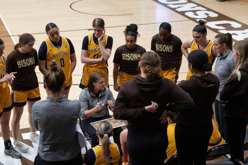 Michèle Sung surrounded by the Bisons women's basketball team during a huddle