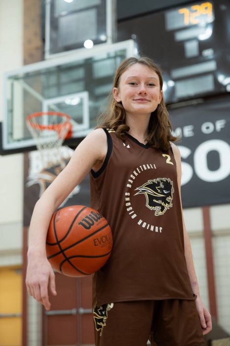 A Junior Bisons athlete stands with a basketball