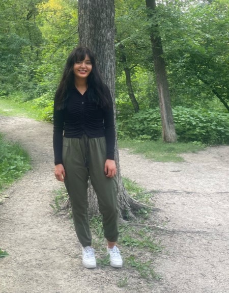 Student Brooke Anderson Baptiste stands outside in front of a tree, smiling at the camera.