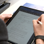 A hand with a digital pen solving a math problem on an iPad .