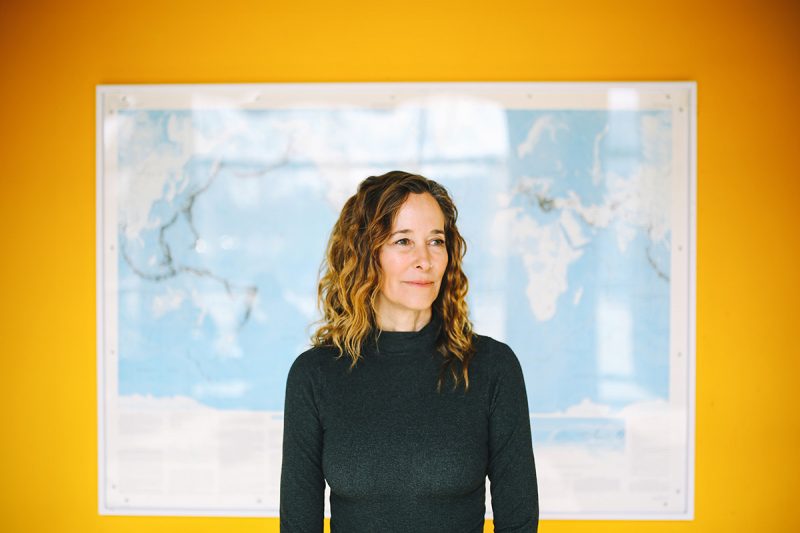 Julienne Stroeve stands in front of a framed map hung on a yellow wall