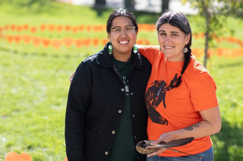 Denise Tardiff, Manager, Manitoba Collaborative Indigenous Education Blueprint puts her arm around Lead Indigenous Engagement, Kayla Lariviere in front of the 2024 Heart Garden