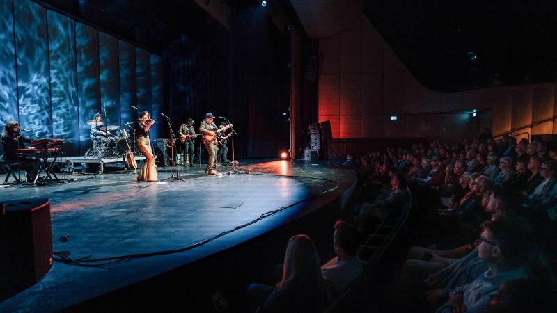 William Prince and his band play on the stage, with the first rows of the audience appearing on the bottom right