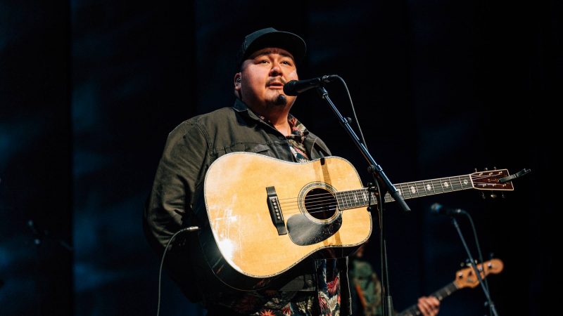 William Prince sings into a microphone from the stage