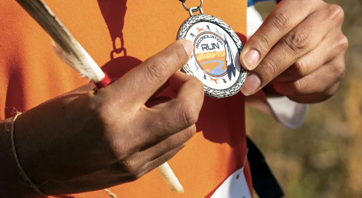 A participant holding a medal and a feather