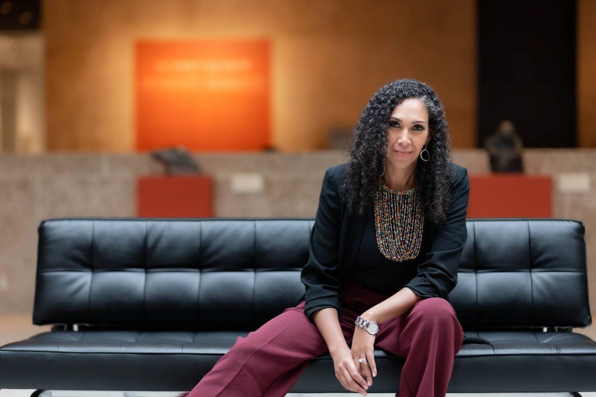 Portrait of Laurel Harris seated on a black sofa at the Winnipeg Art Gallery. photo by Reanna Khan.