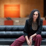 Portrait of Laurel Harris seated on a black sofa at the Winnipeg Art Gallery. photo by Reanna Khan.